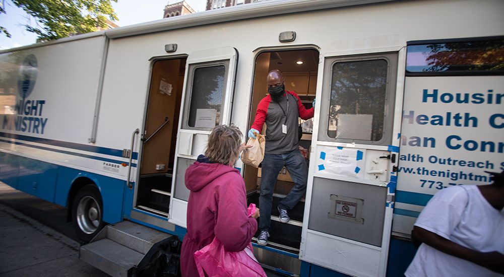 Outreach Professional Lavelle Horne offers a sack supper to a Health Outreach Bus visitor.